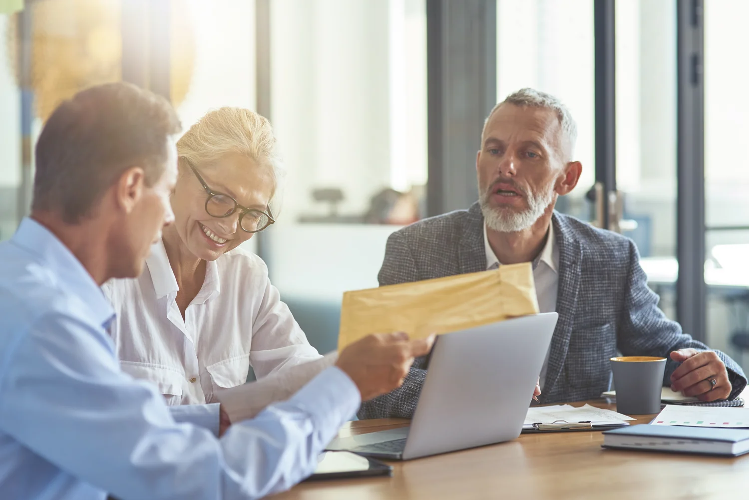 Drie professionals bespreken documenten aan een bureau